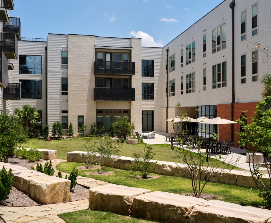 rendering of property entrance and exterior showing modern landscaping and spacious areas to access building
